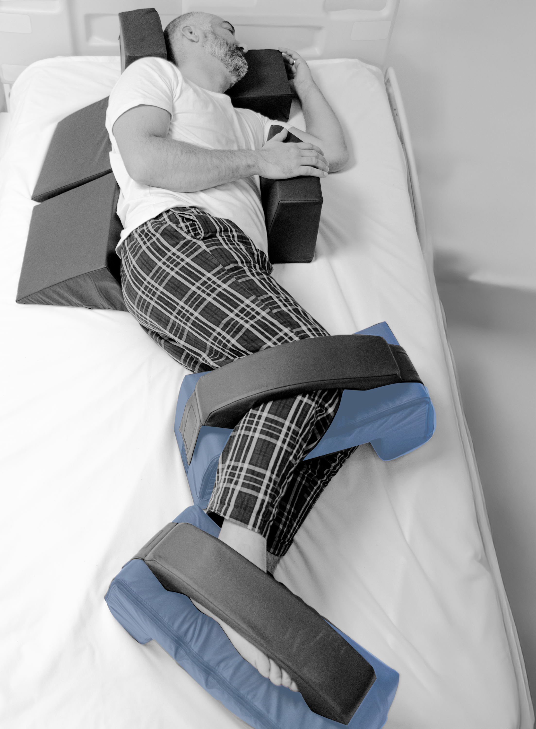 Person lying on a medical device with adjustable supports, with leg bridge cushions highlighted
