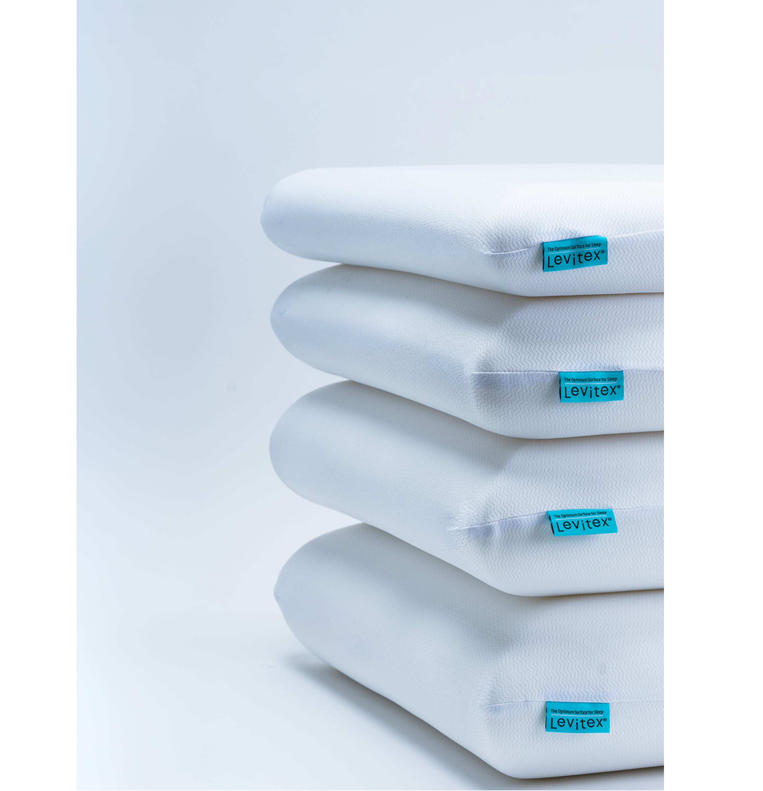 Stack of white pillows in increasing sizes with blue labels on a light gray background