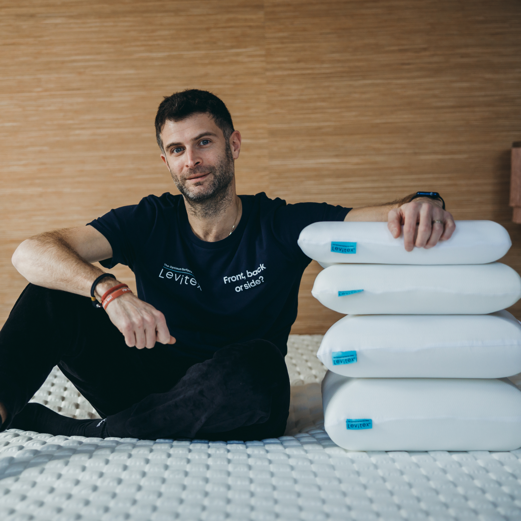 James Leinhardt on bed next to 4 stacked levitex pillows
