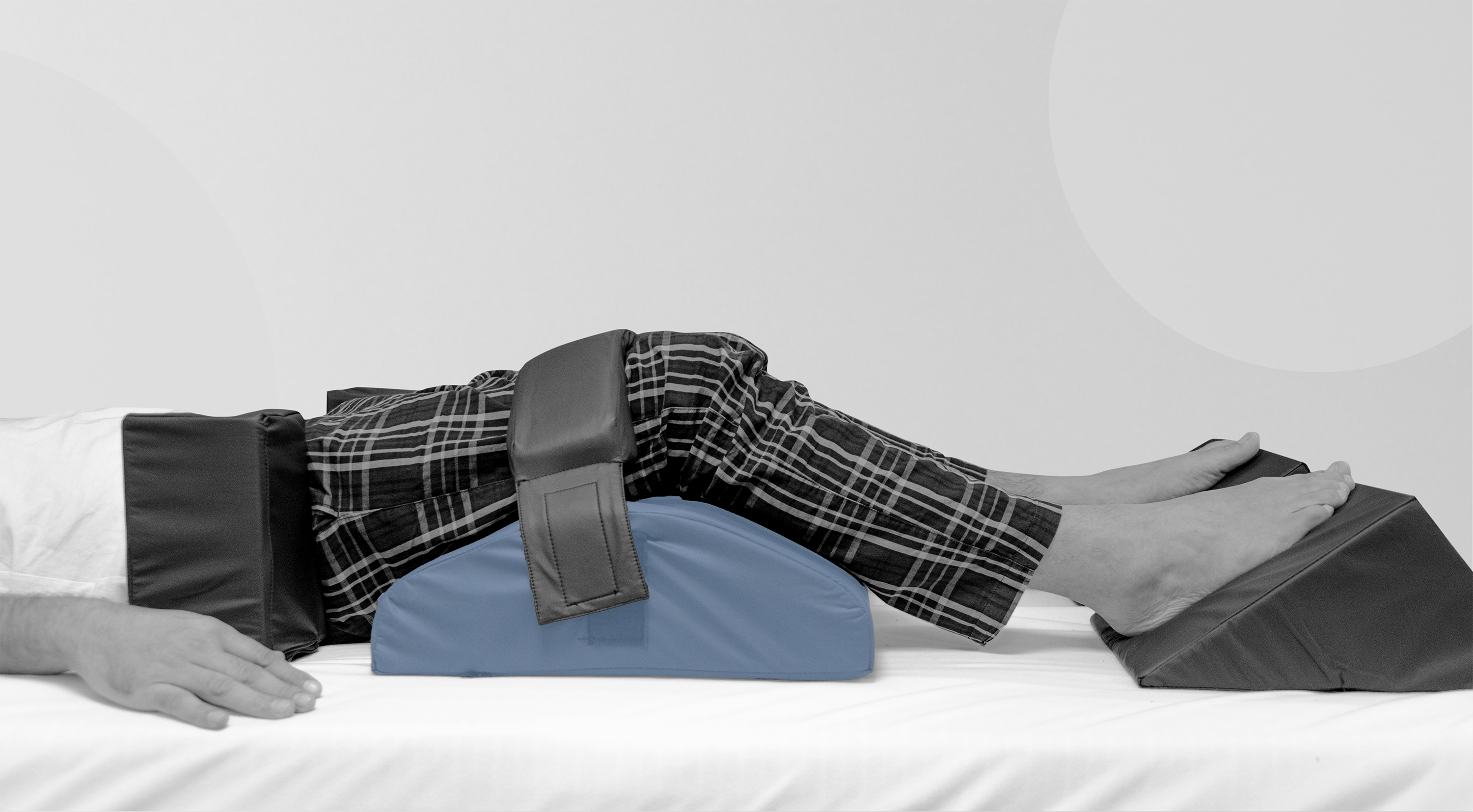 Person's legs lying on a bed with a sleep support system and Knee blockers highlighted