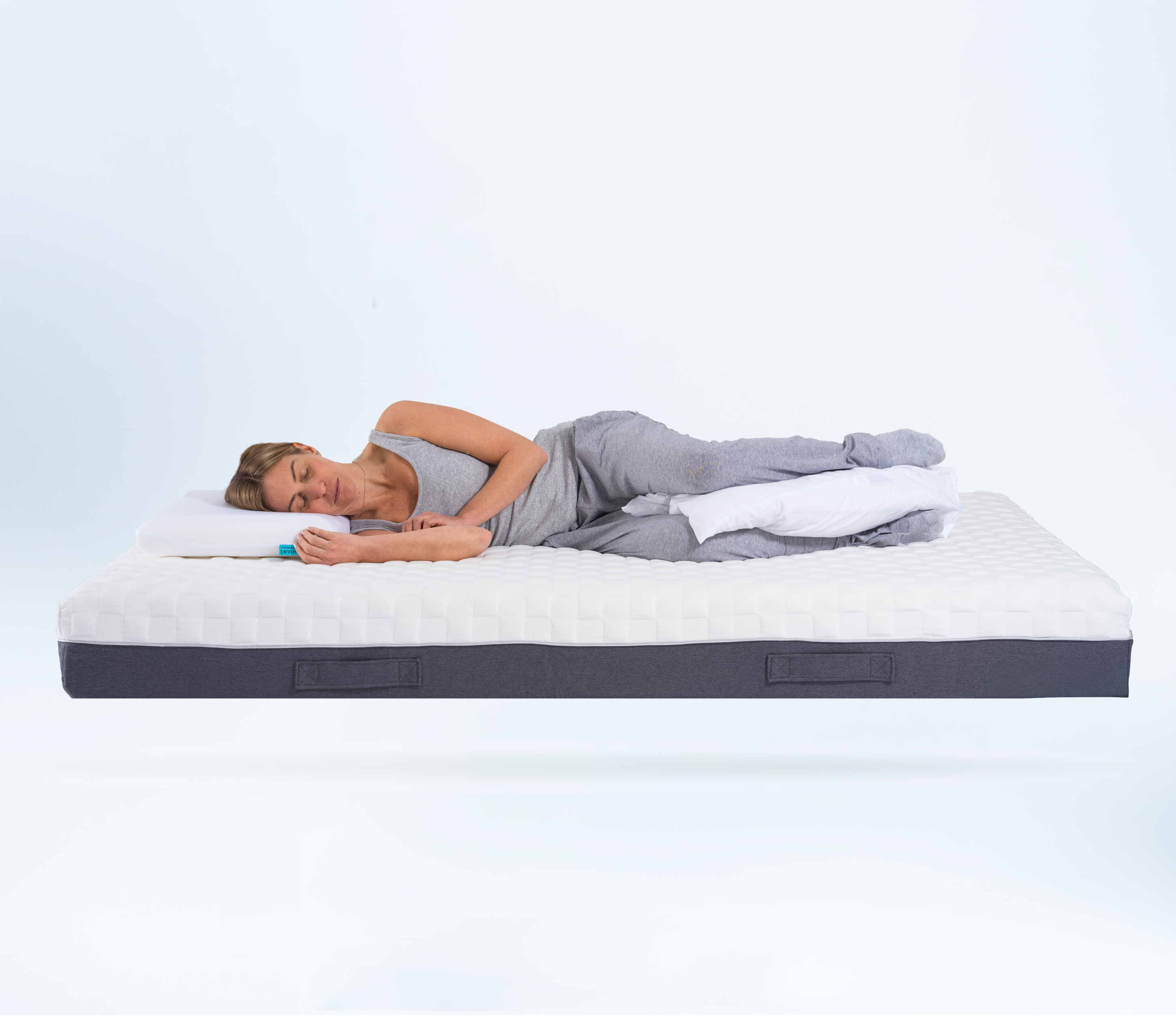 Person lying on a posture mattress with a white background