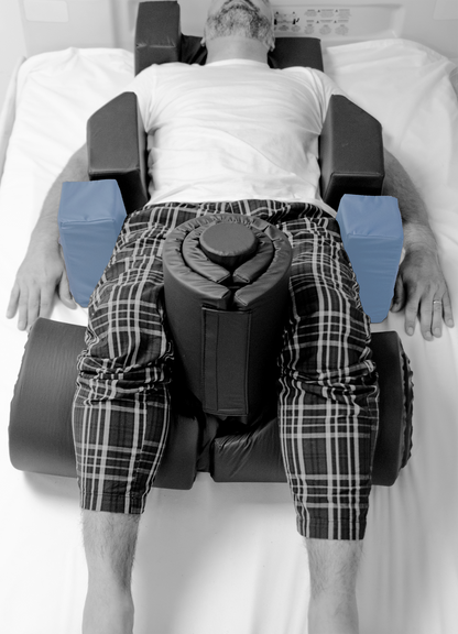 Person lying on a specialized medical device with cushions on a white background
