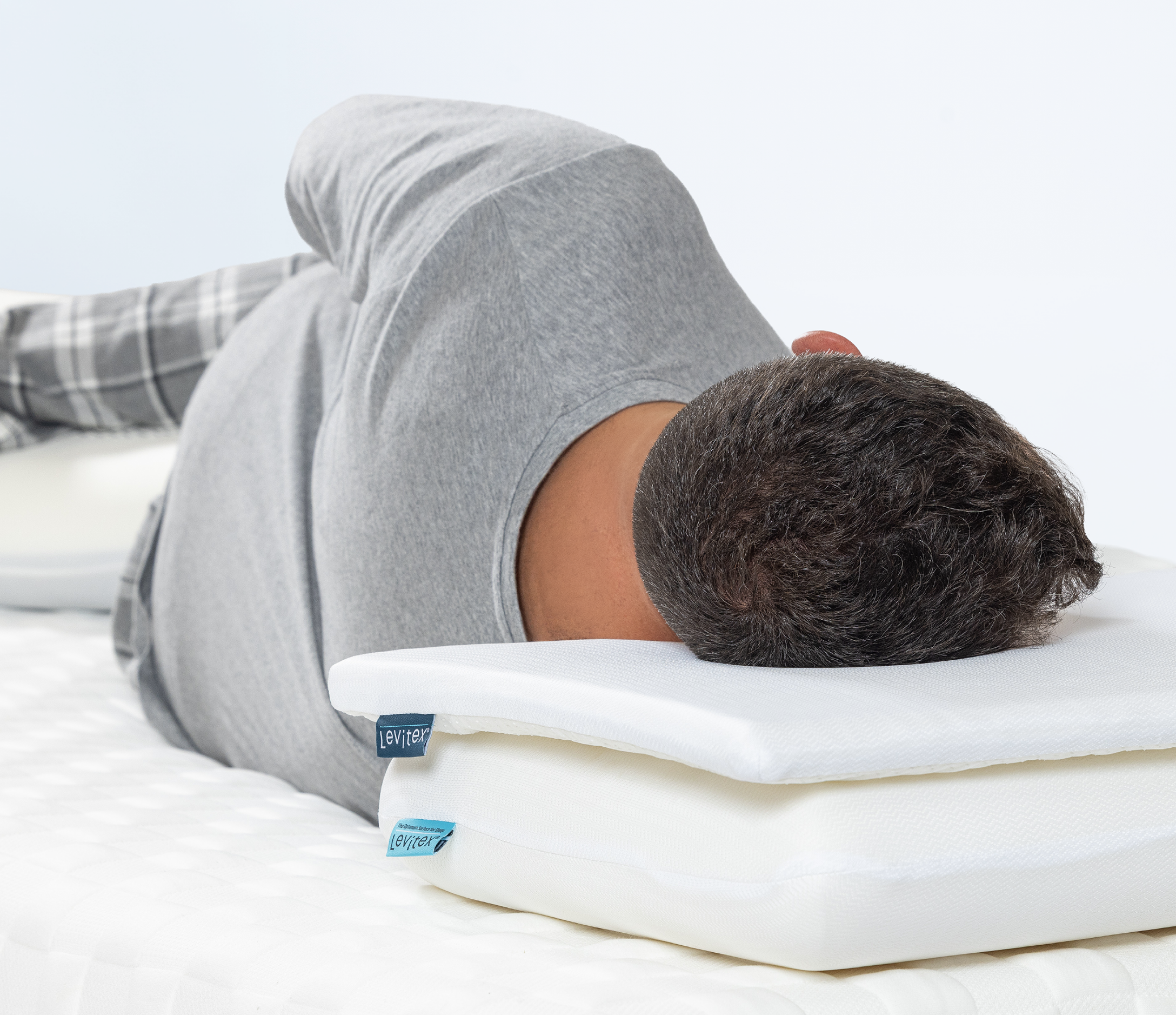 Man lying on his side supported by pillow topper